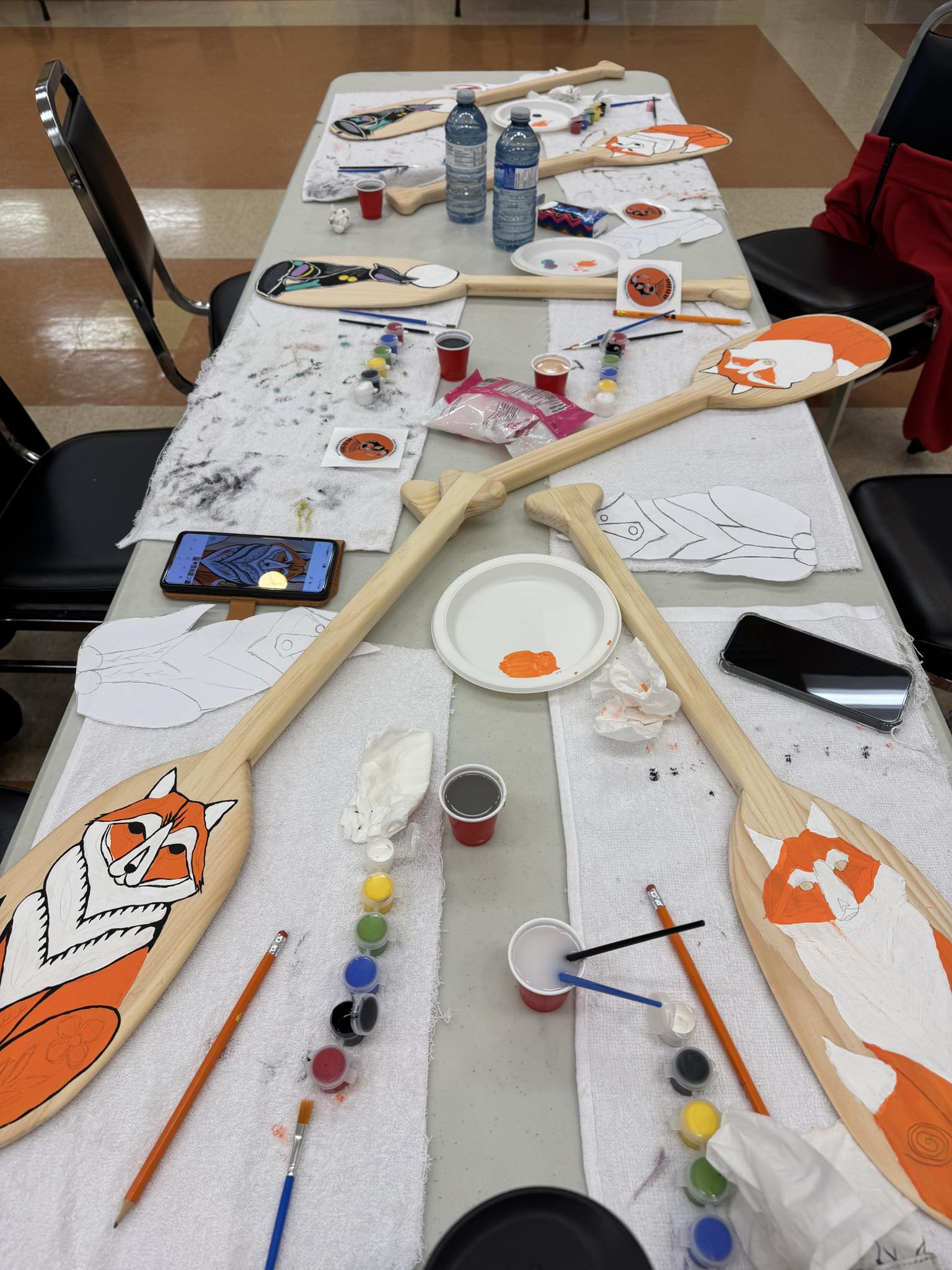 Participants in a Focal Point Artistry workshop actively painting their own Woodland style pieces following an educational talk on Wabanaki design and color symbolism.