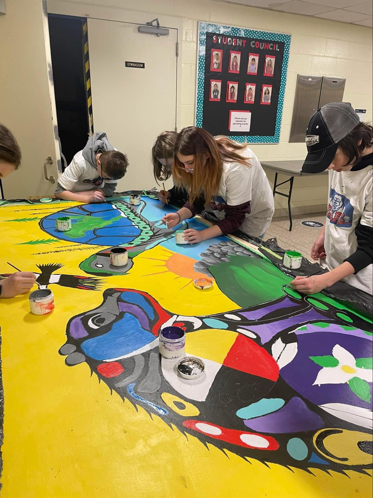 Jessica Somers demonstrating the Woodland style "X-ray" technique to explain the internal spirit and teachings within a vibrant animal painting.