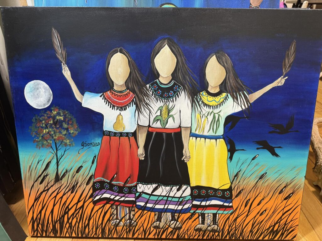 Jessica Somers creating Woodland style Indigenous art, applying bold black lines and vibrant colors to canvas to depict Wabanaki stories.